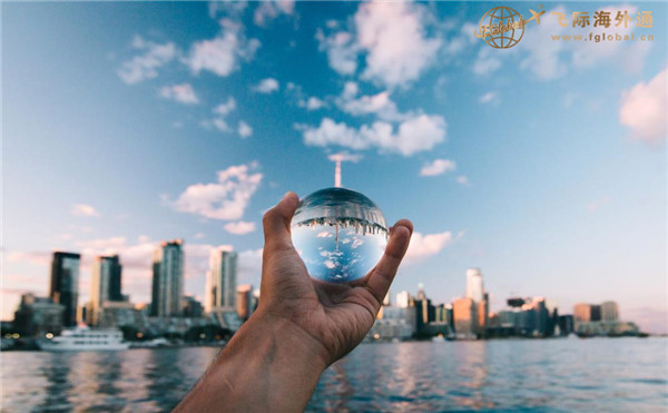 一只手拿着一个玻璃球看城市建筑